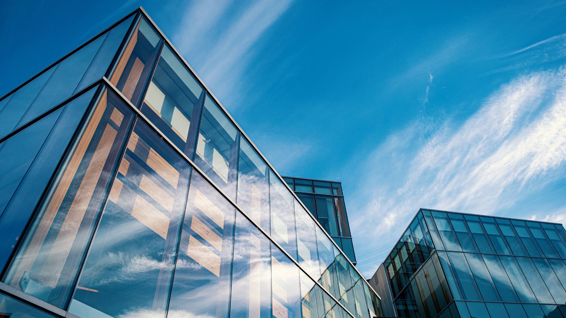 Glass commercial building facade reflecting the sky