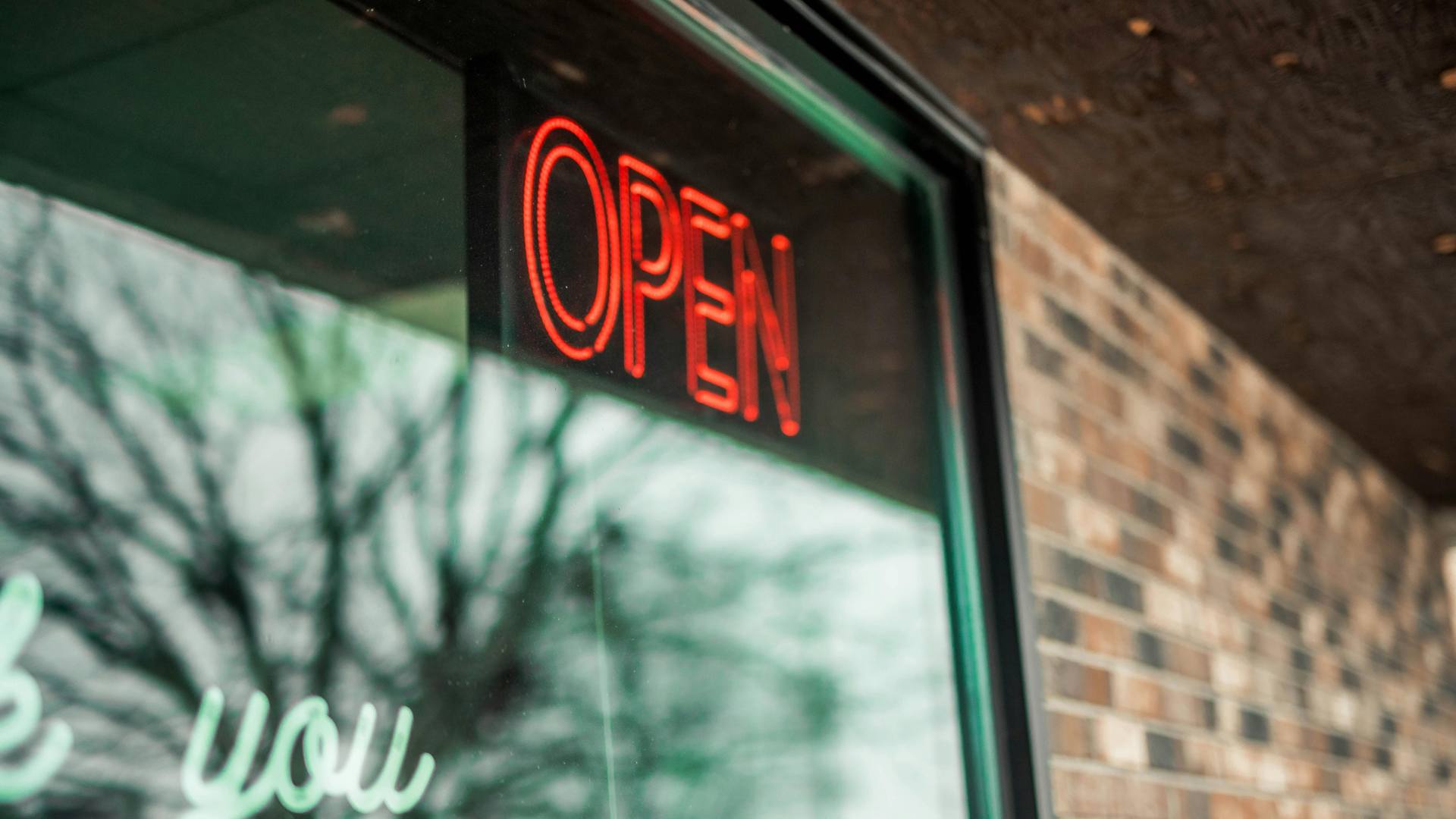 Neon open sign glowing in a storefront door window